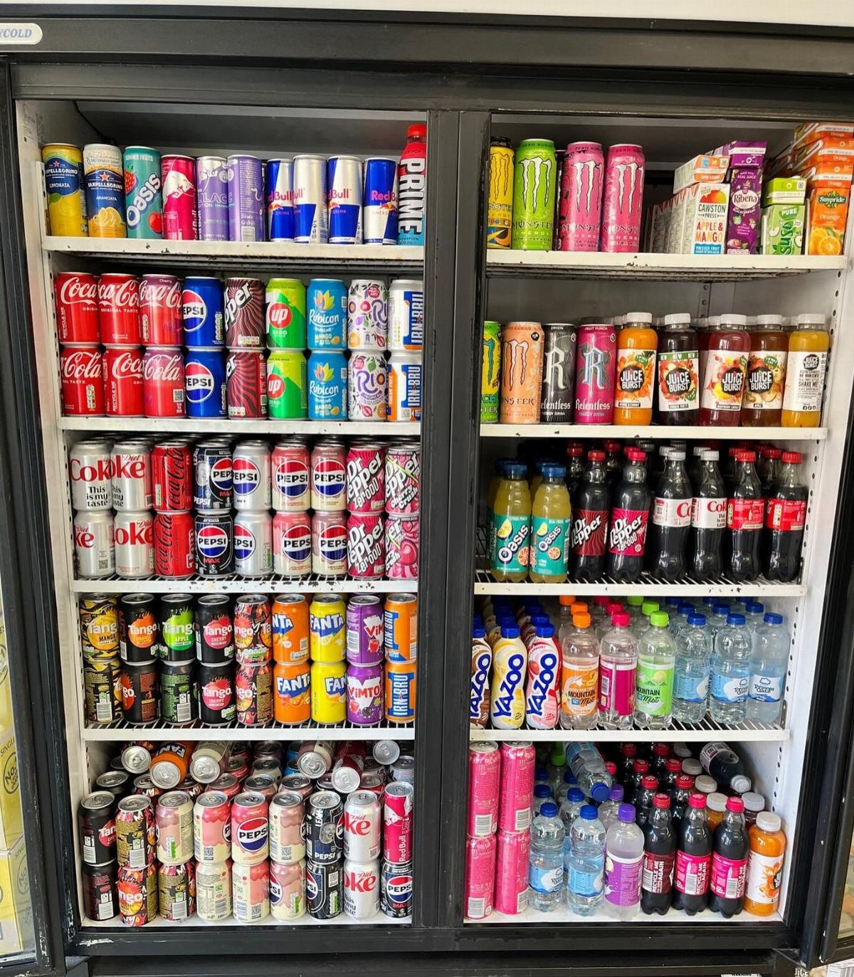 A large black refrigerator stocked with many rows of colorful canned and bottled drinks.