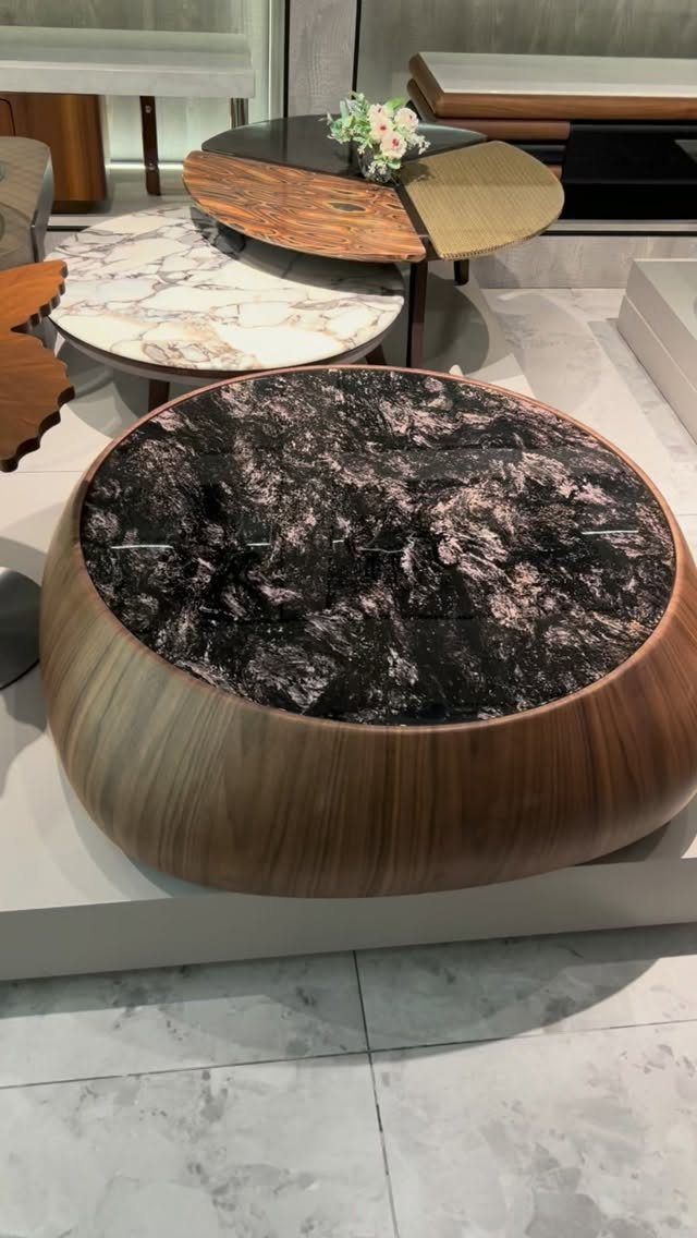 A round coffee table with a dark marbled top and a smooth wooden base.