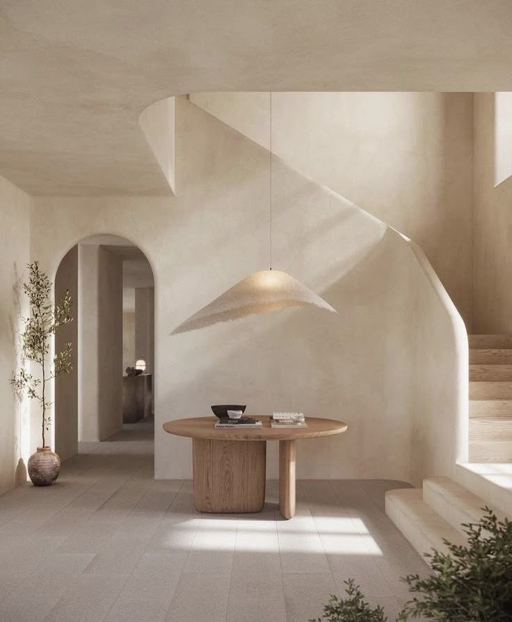 Minimalist room featuring a large arched doorway, curved staircase, and a wooden pedestal table.