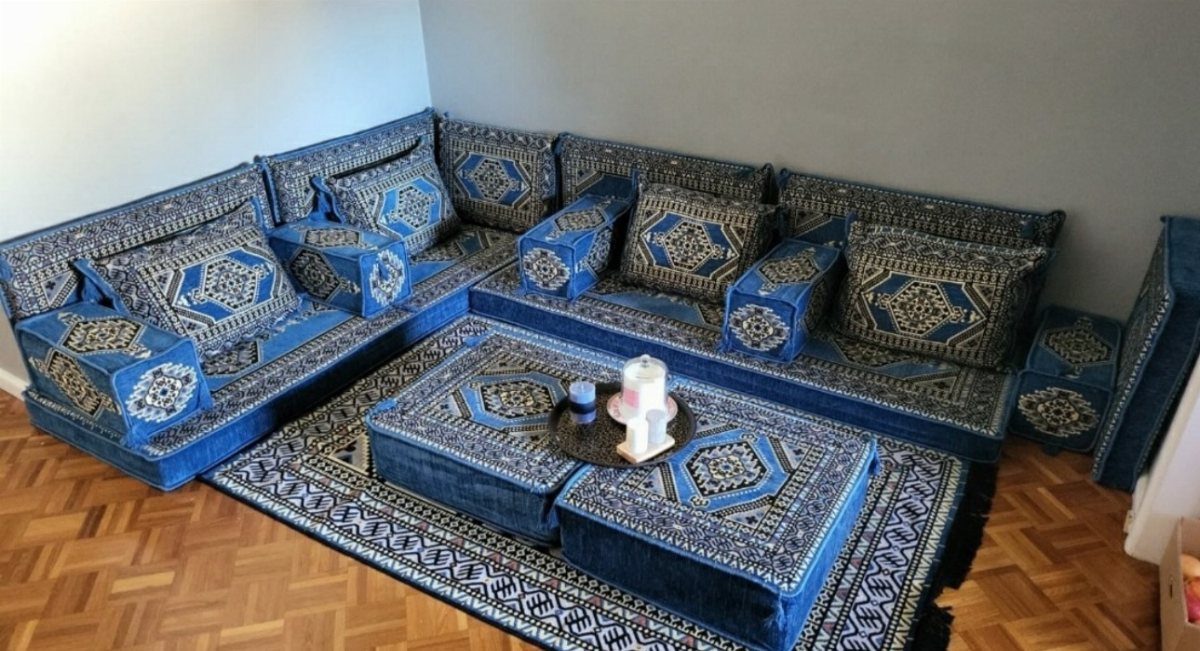Blue patterned floor seating and cushions arranged around a central ottoman on a wooden floor.