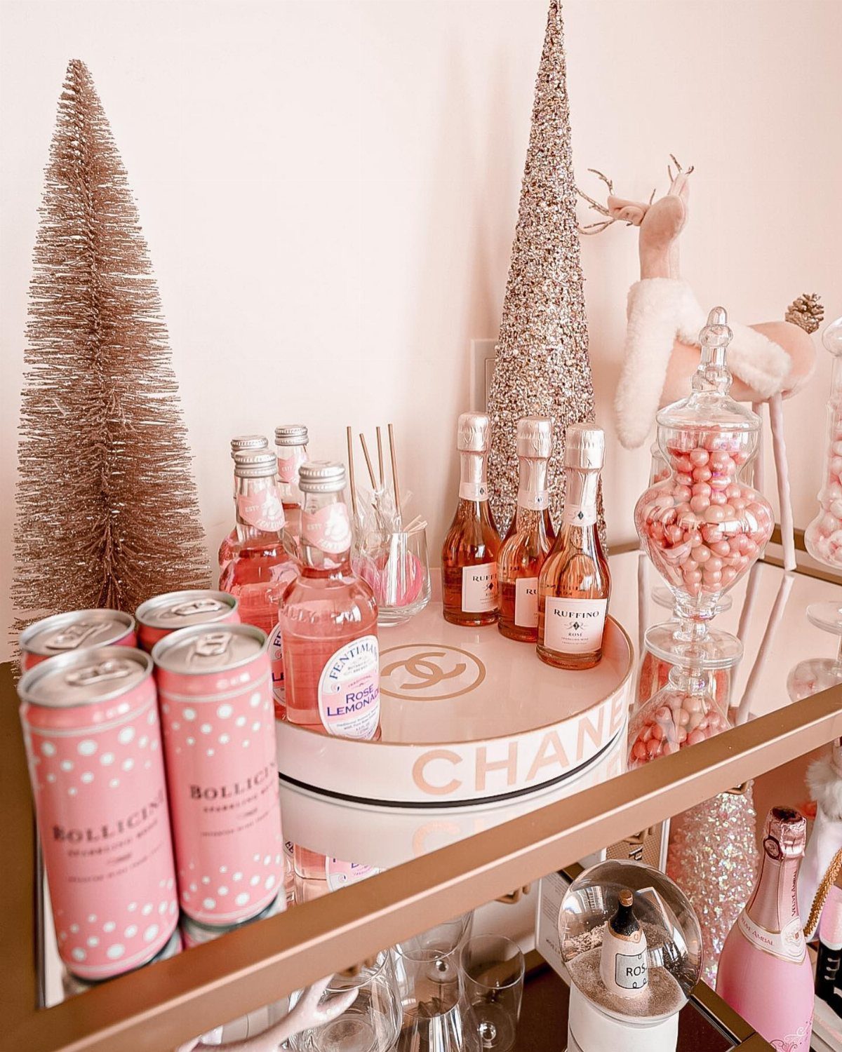 Pink beverages and rose gold trees arranged on a gold bar cart.