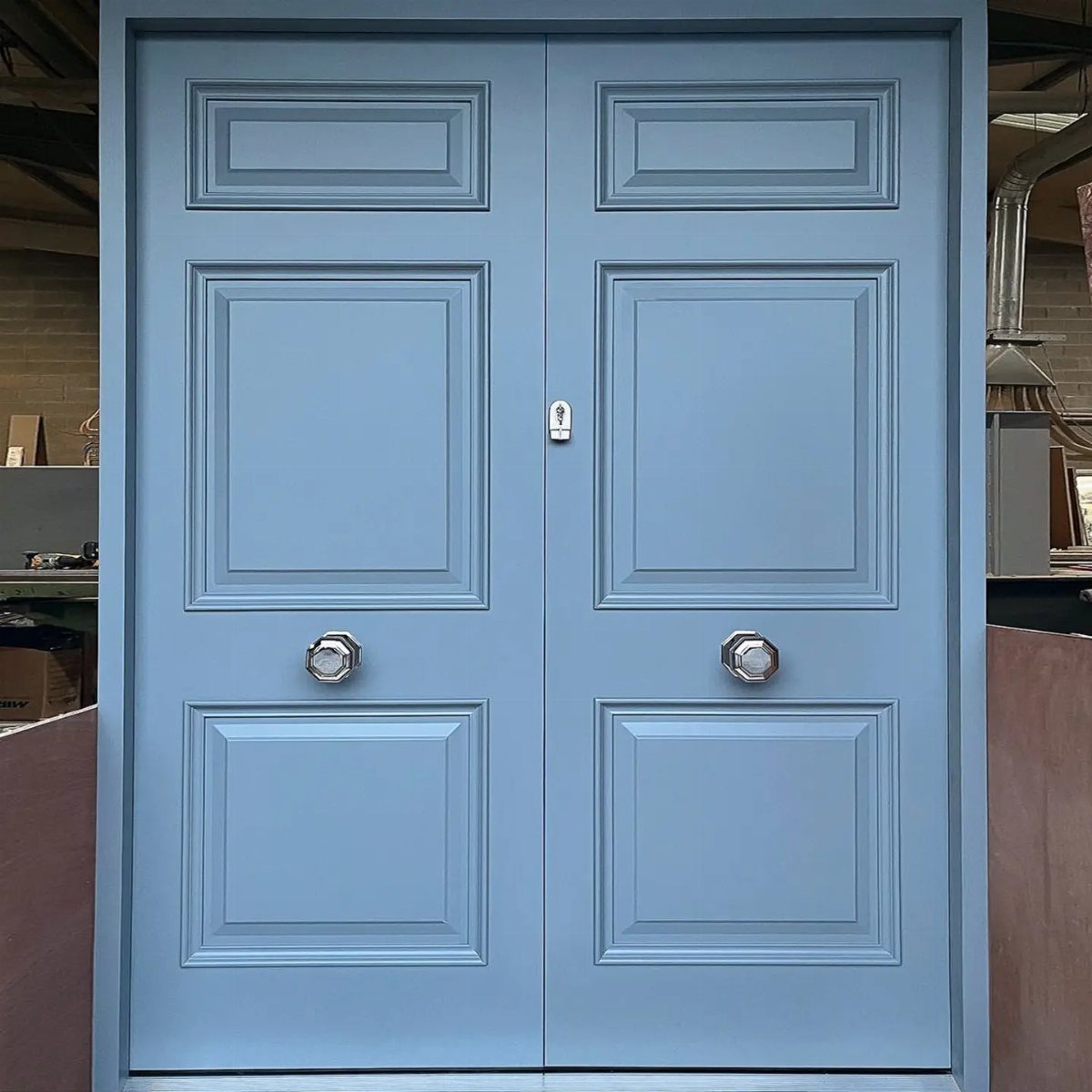 Light blue double doors with silver hexagonal knobs and recessed rectangular panels.