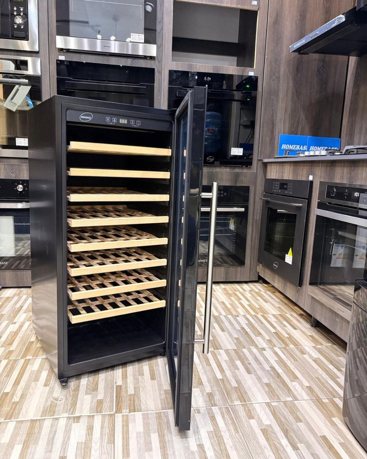 Open black wine cooler with wooden storage racks in a modern kitchen setting.
