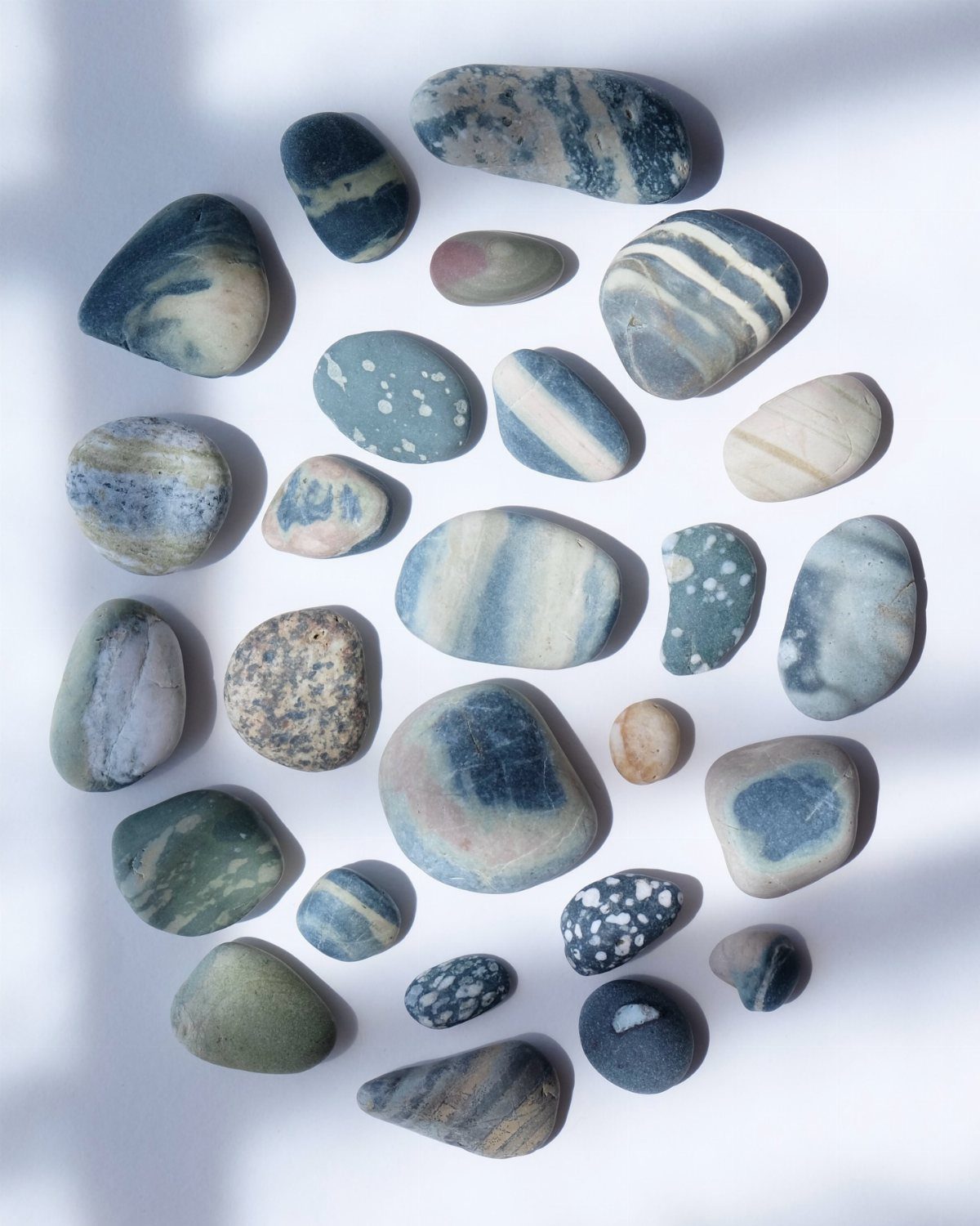 Smooth, multicolored beach stones arranged in a circular pattern on a white background.
