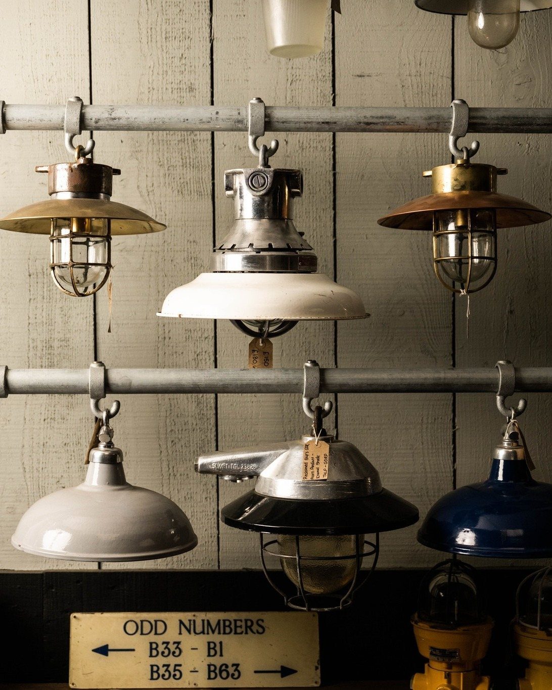 Industrial metal pendant lights with wire cages hanging against a white wooden plank wall.