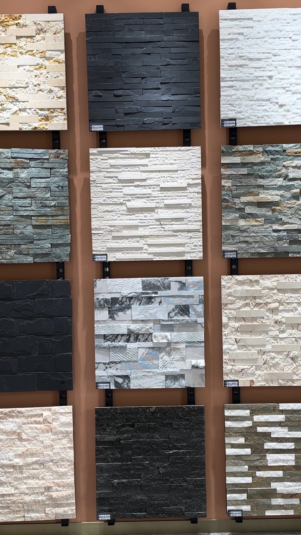Various rectangular natural stone tile samples in different colors and textures displayed on a wall.