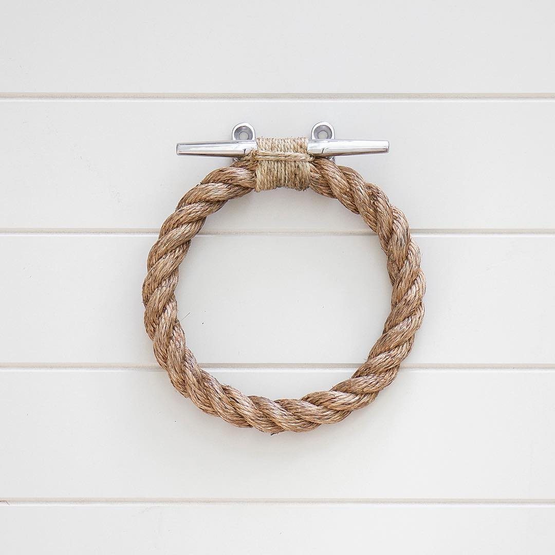 A thick natural rope towel ring mounted on a white shiplap wall.