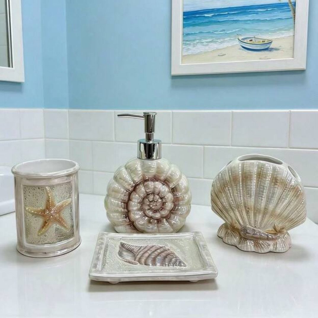 Seashell-themed bathroom accessories including a soap dispenser and starfish toothbrush holder on a white counter.