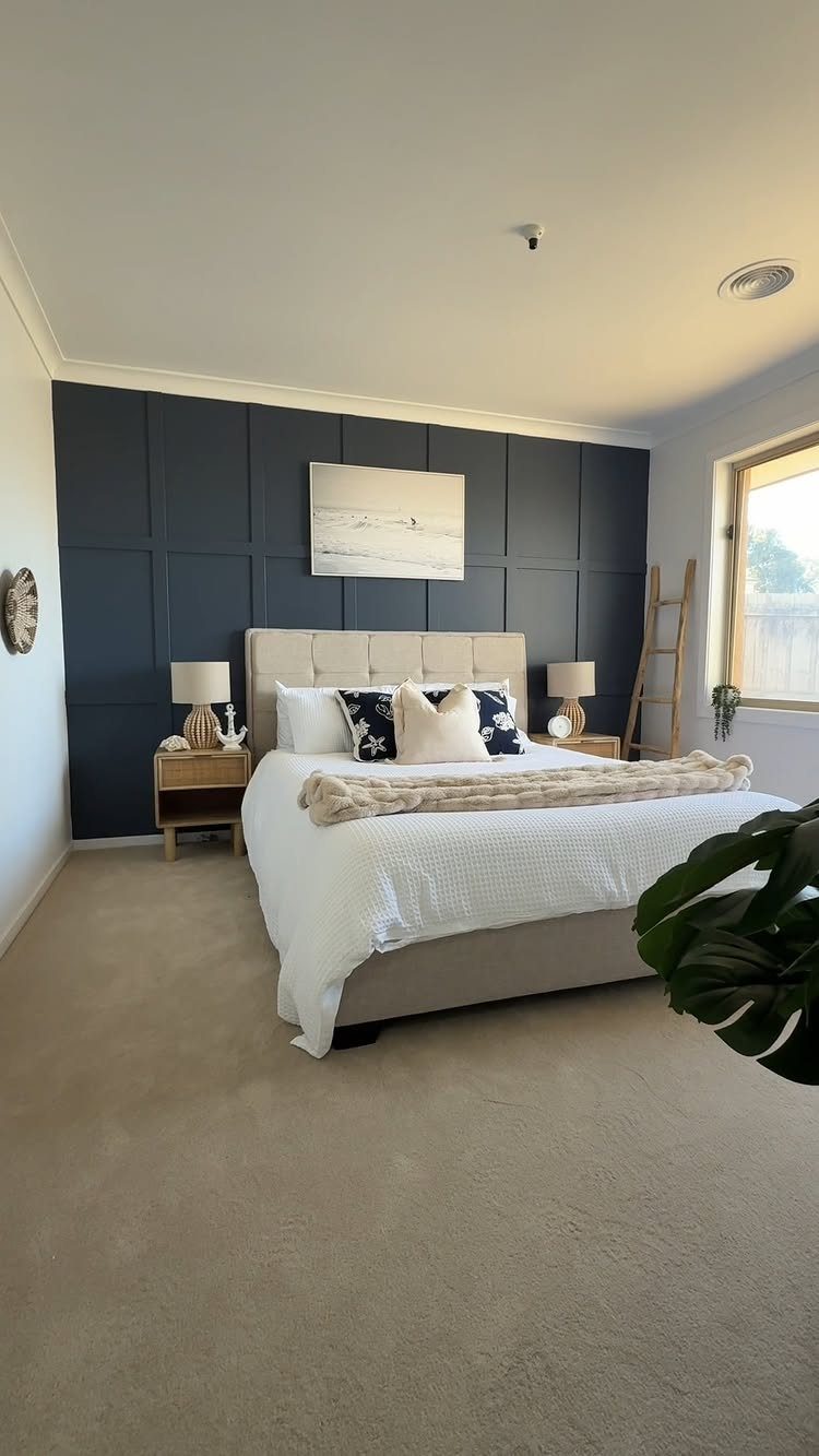 Navy blue board and batten accent wall behind a large beige bed in a bright bedroom.