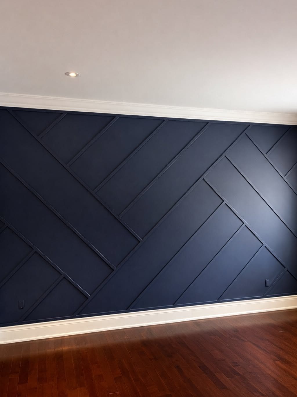 Navy blue accent wall with a raised geometric pattern and dark wood floors.