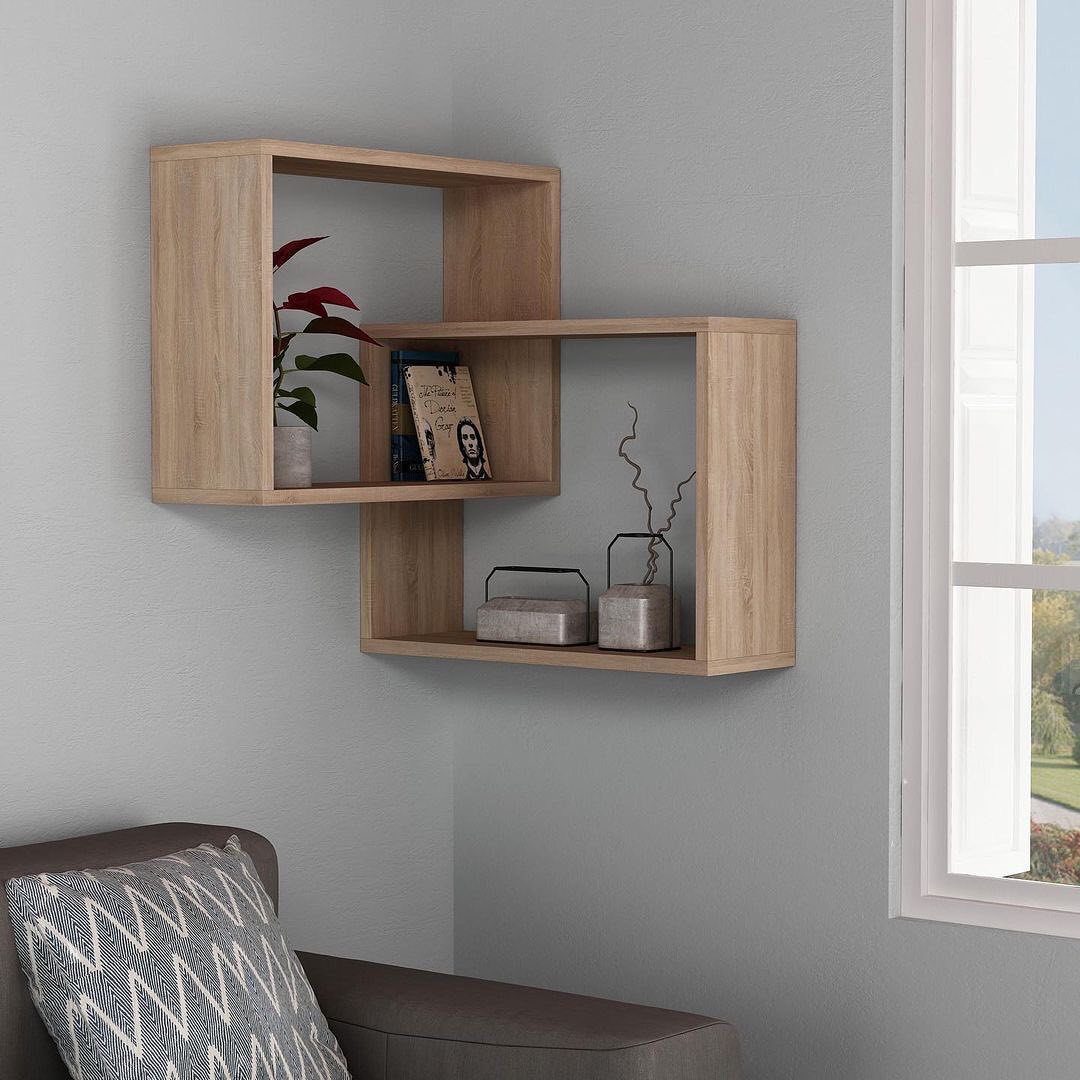 Light wood grain cube floating shelves holding books and plants in a grey corner.