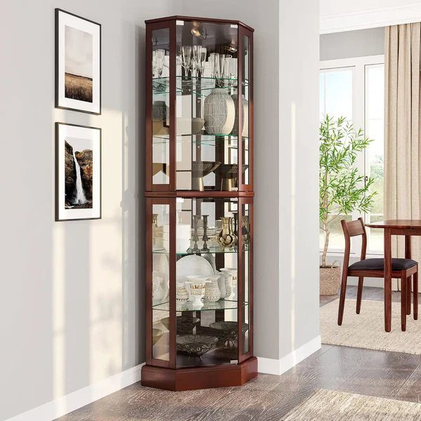 Tall dark wood corner cabinet with glass doors displaying glassware and ceramics in a bright room.