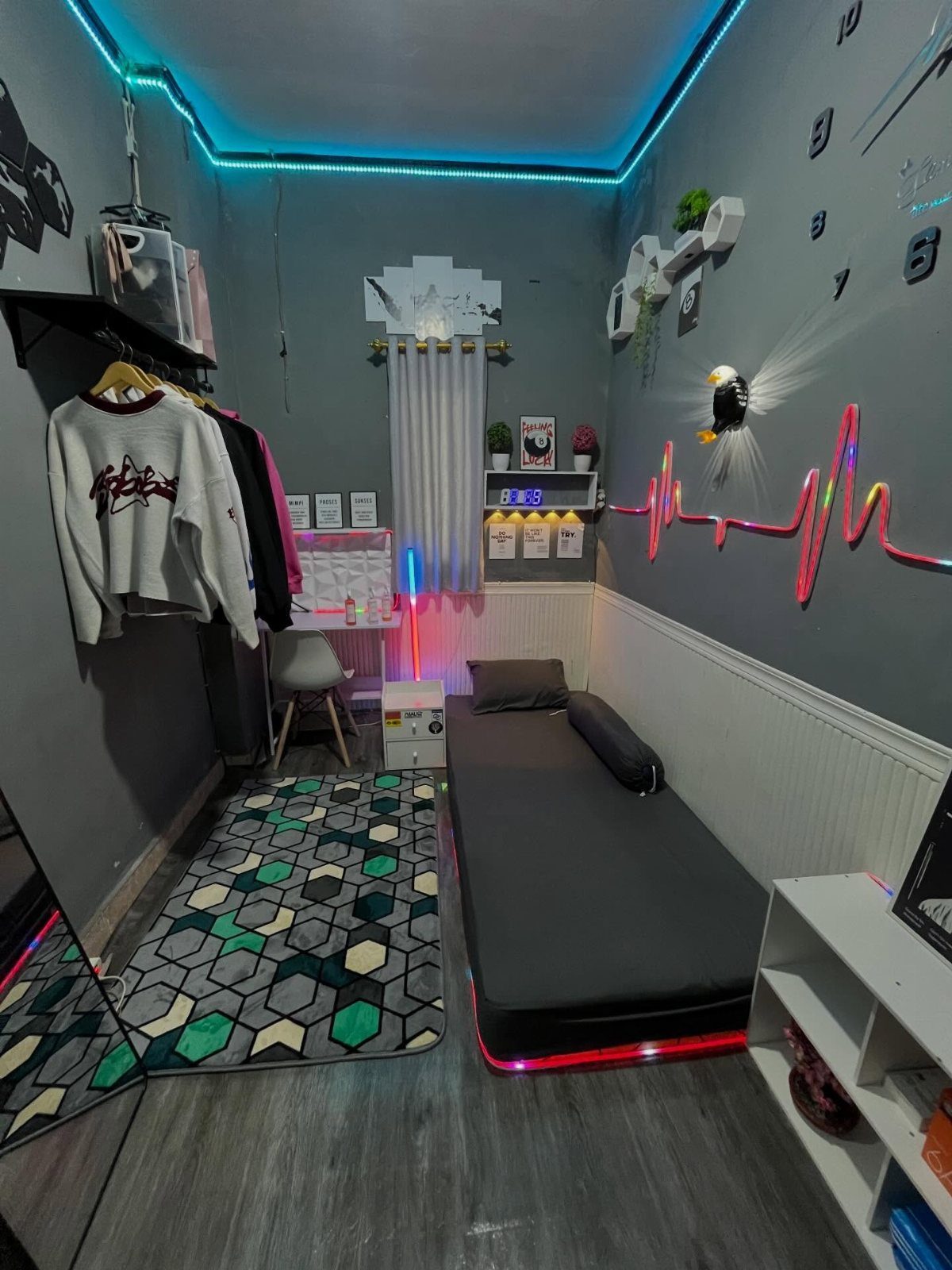 A small bedroom with grey walls, blue LED lighting, and a black daybed.