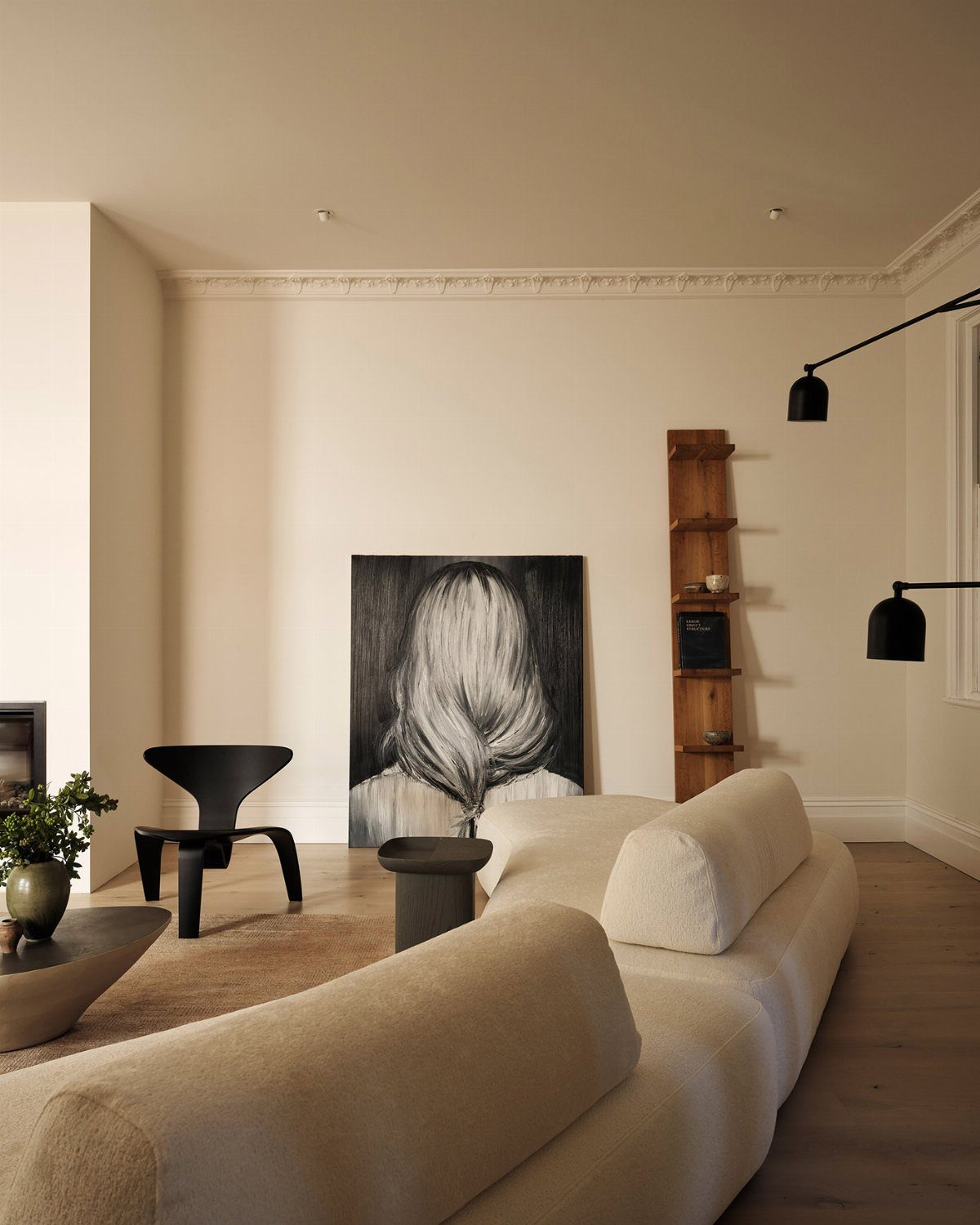 Large black and white portrait leaning against a minimalist cream wall in a modern room.