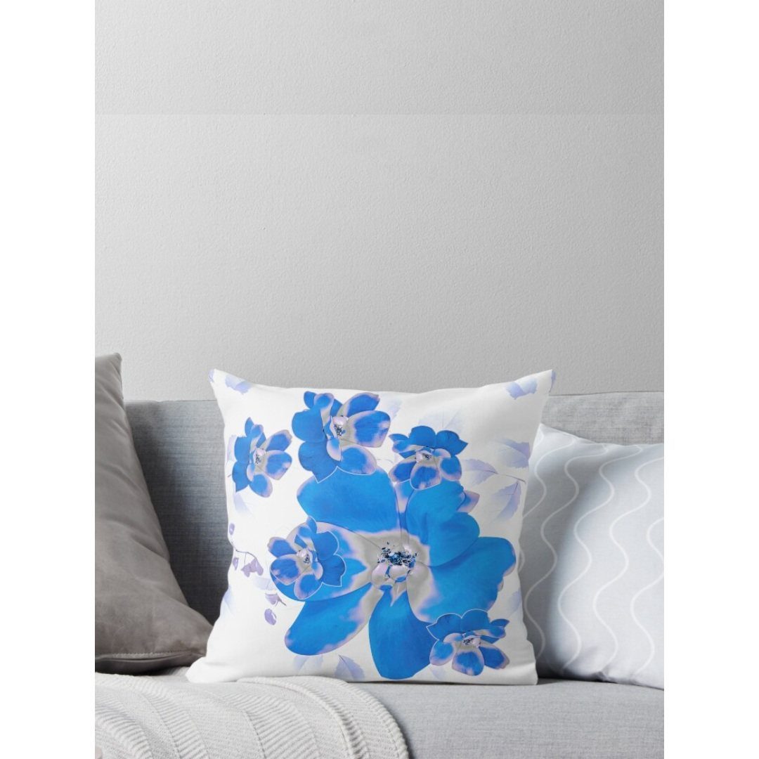 Blue floral patterned throw pillow resting on a grey sofa with other pillows.