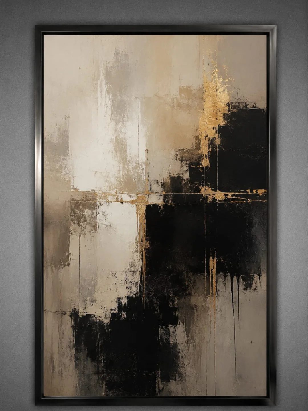Abstract black, cream, and gold textured painting in a dark frame on a grey wall.