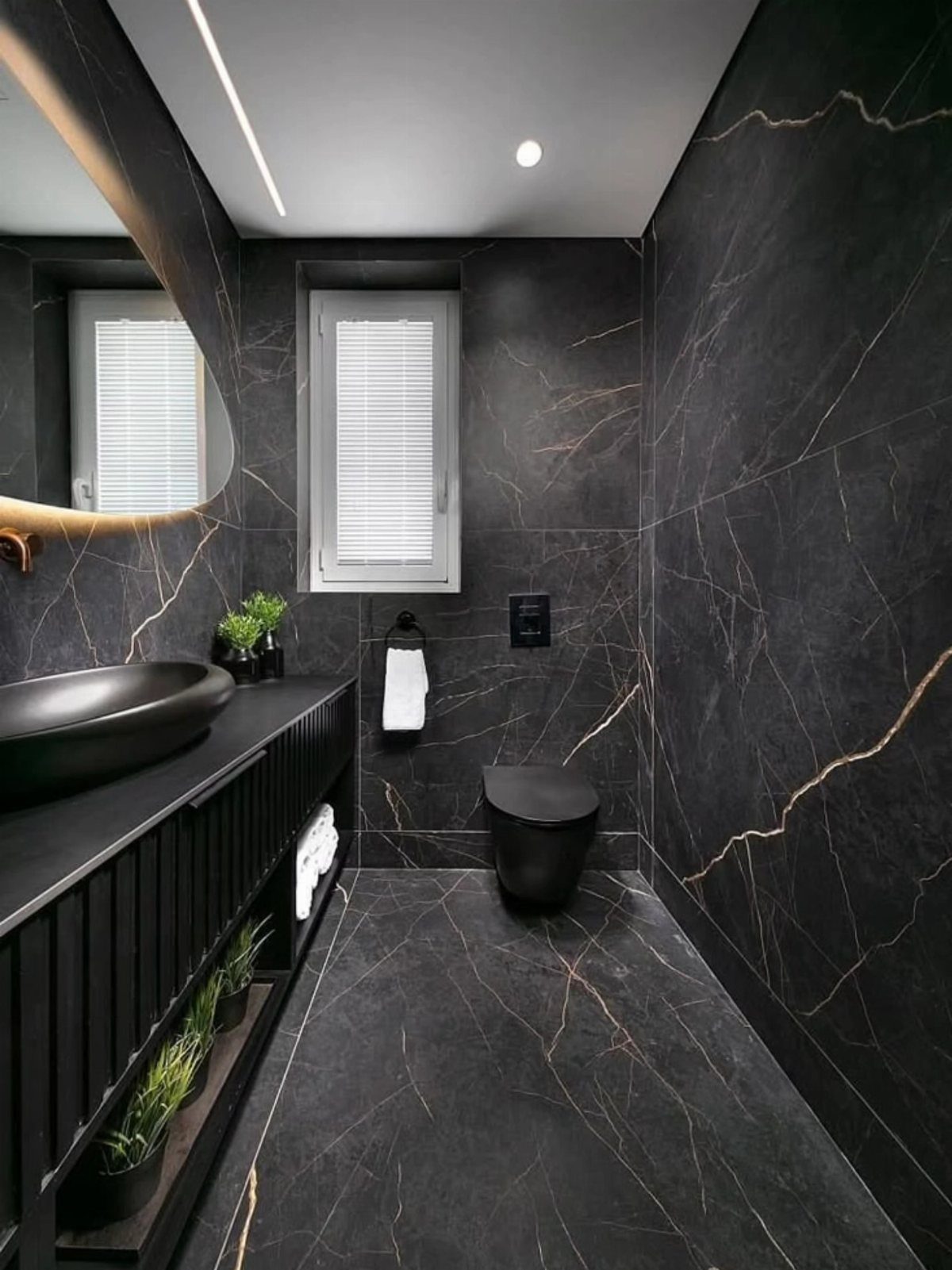 Black marble tiles with gold veining covering the walls and floor of a modern bathroom.
