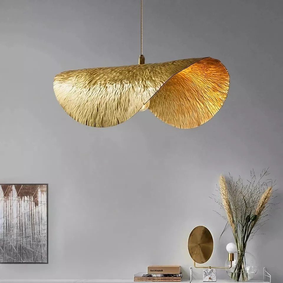 Large textured gold pendant light hanging against a grey wall above a minimalist side table.