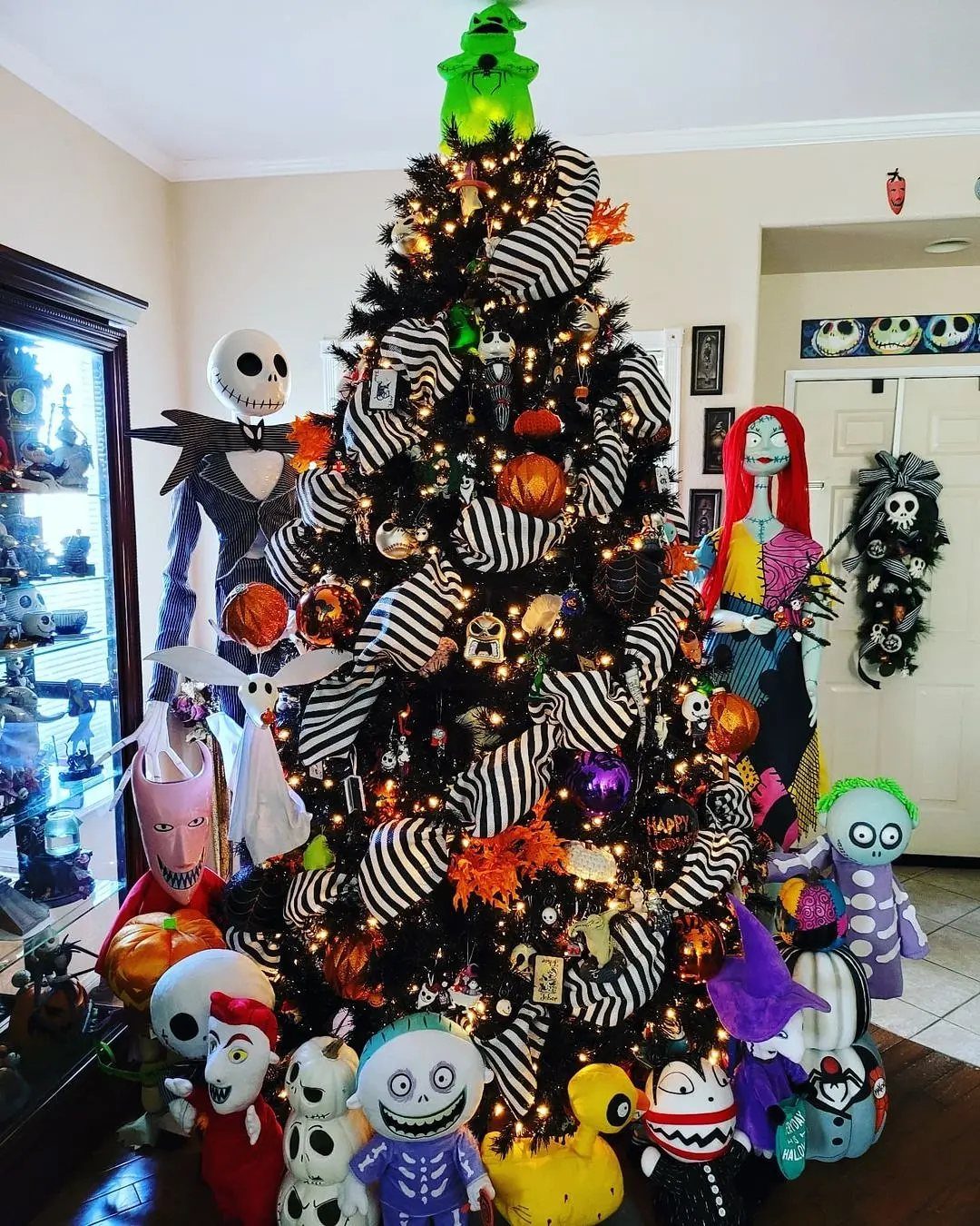 Black Christmas tree decorated with Nightmare Before Christmas themed ornaments and striped garlands.