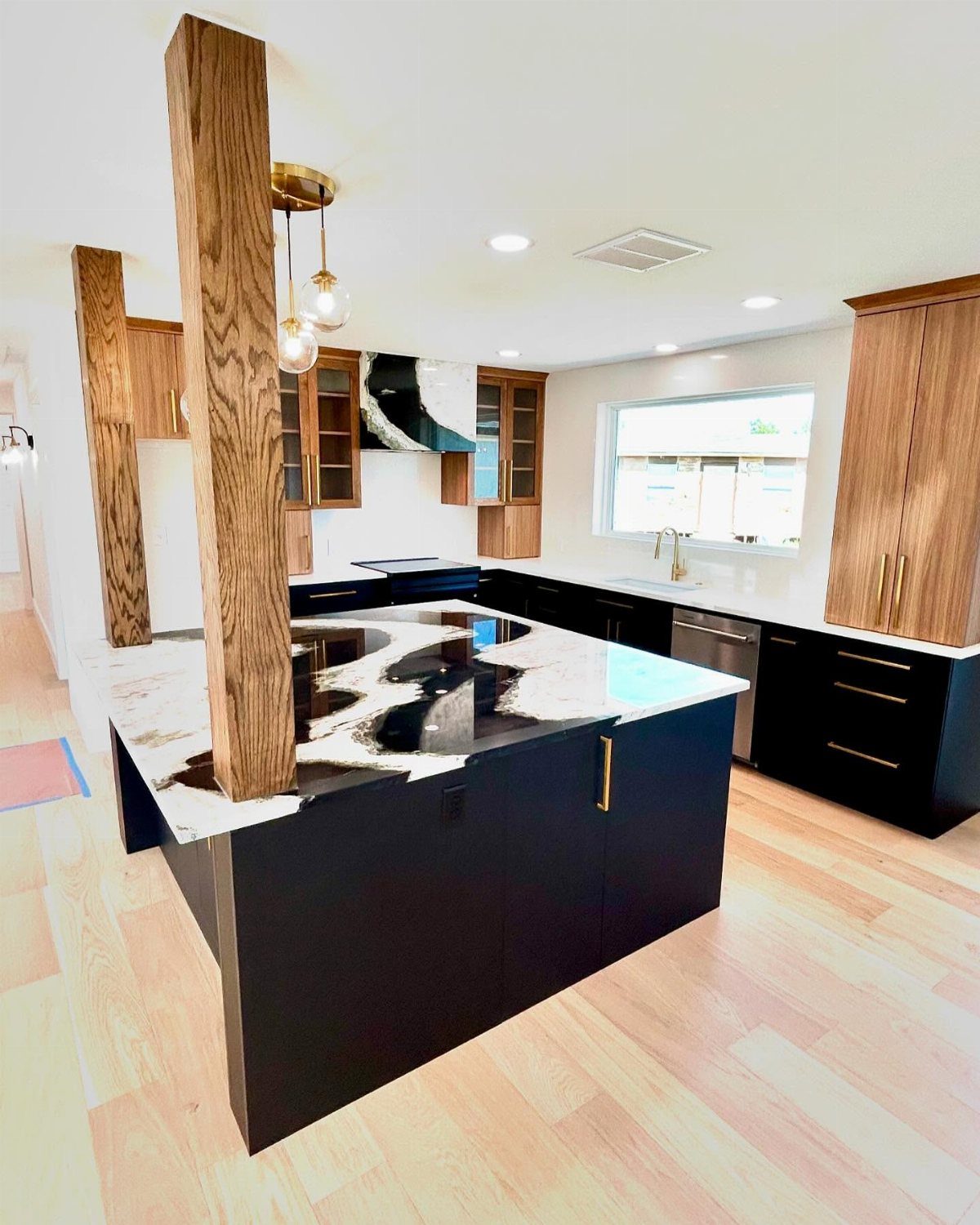 Black base cabinets with a marbled countertop and gold hardware in a modern kitchen.