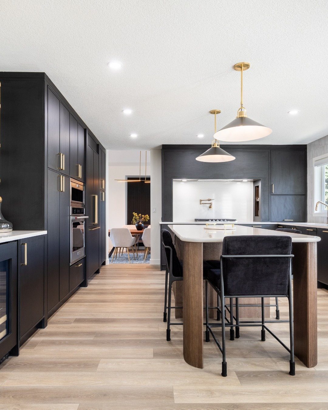 Black kitchen cabinets with gold hardware, white subway tile backsplash, and gold pendant lighting.
