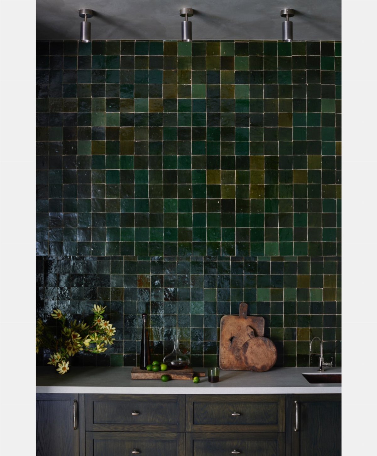 Black kitchen cabinets featuring a glossy dark green tiled backsplash and white countertop.