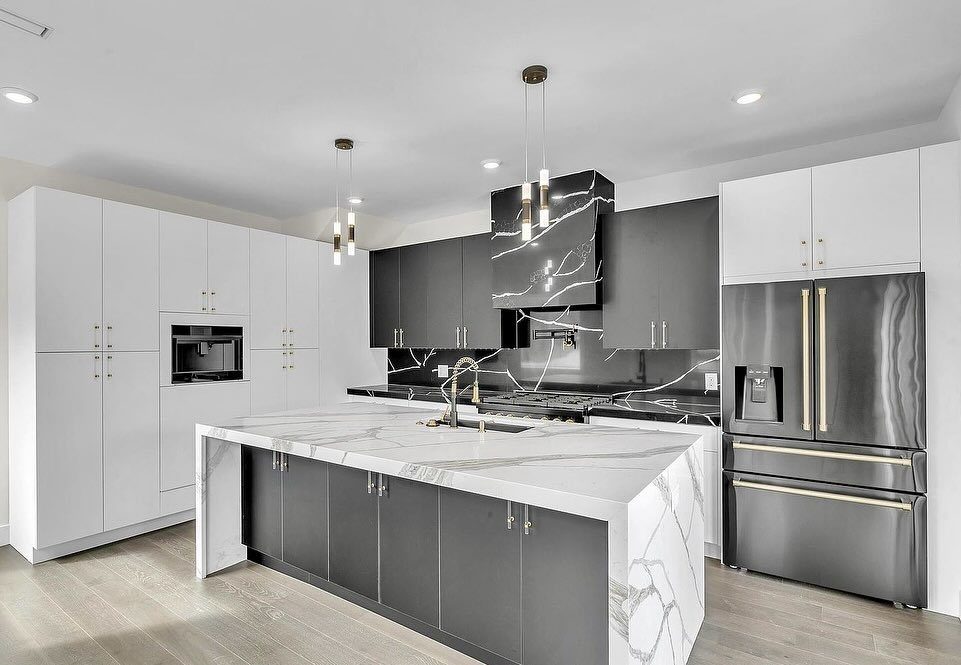 Modern kitchen with black lower cabinets, white upper cabinets, and white marble countertops.