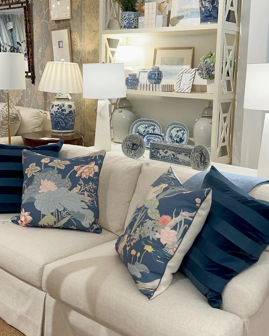 Cream sofa with navy blue floral and striped pillows in a decorated living room.