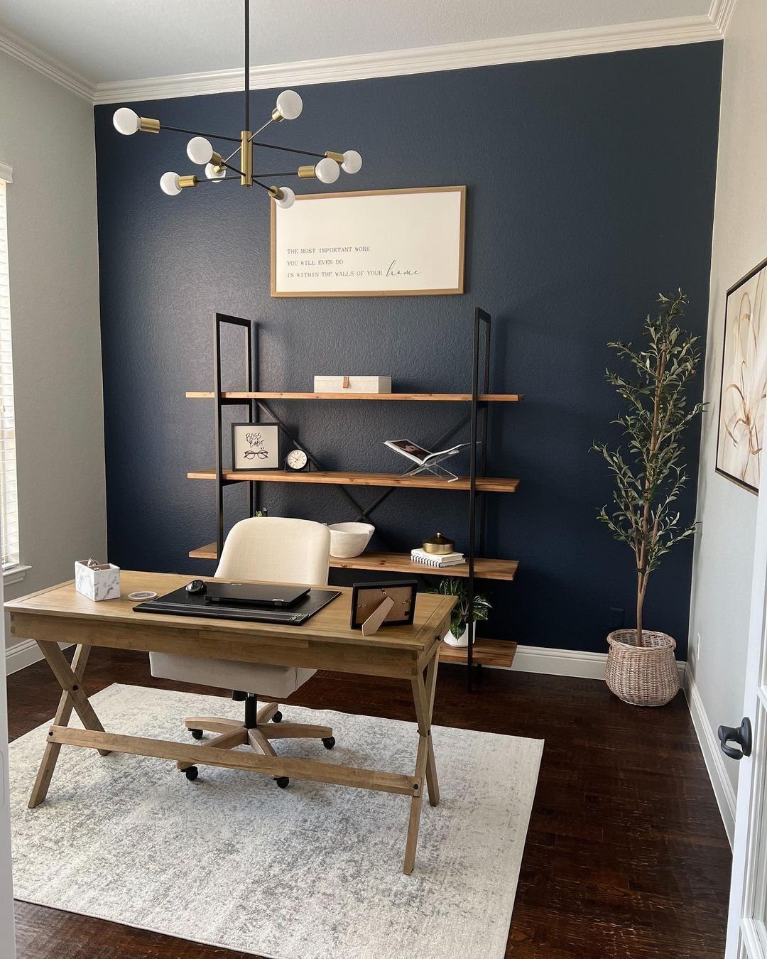 Navy blue accent wall behind a wooden desk and cream office chair in a room.