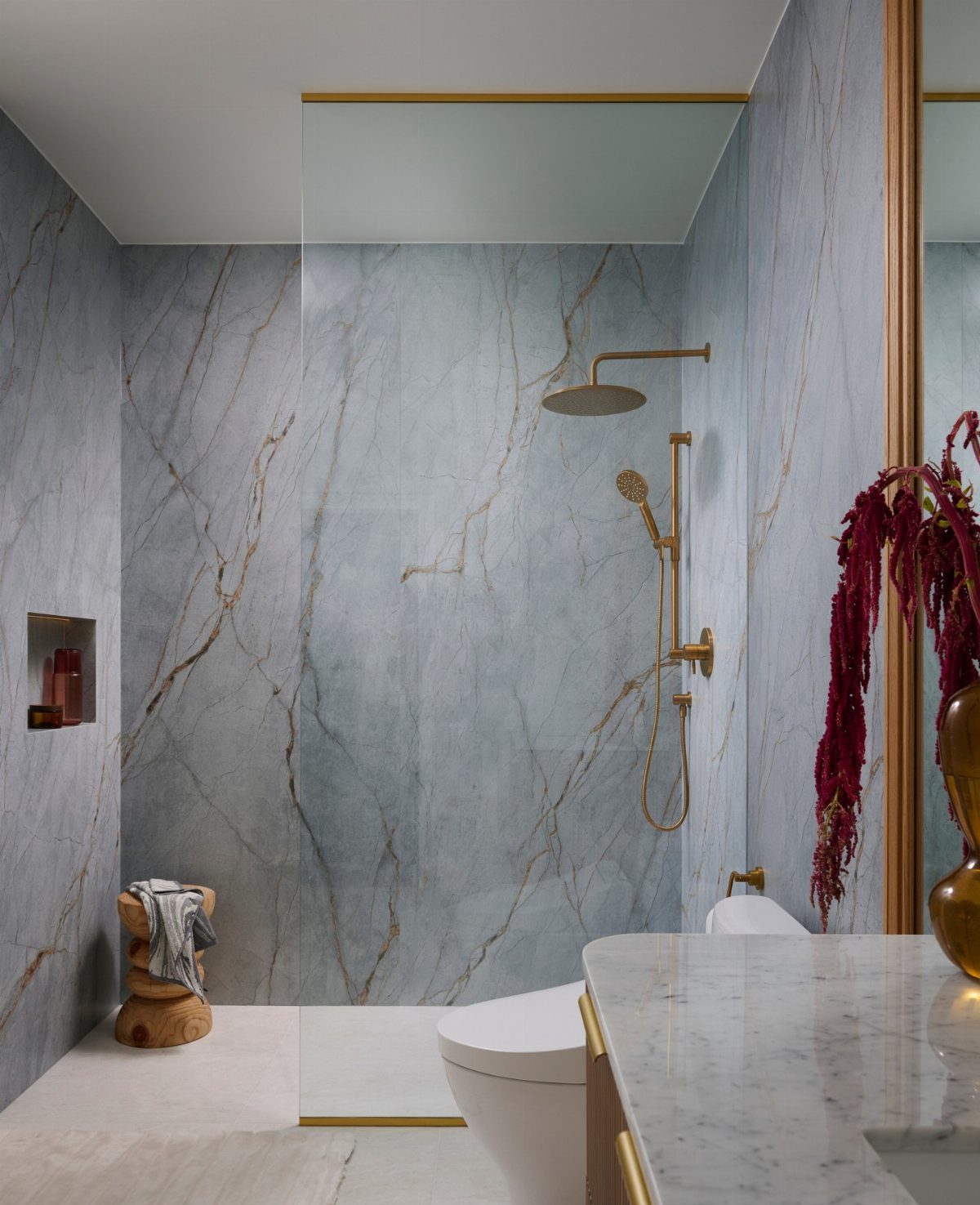 Light blue marble tiles with gold veining and gold shower fixtures in a modern bathroom.