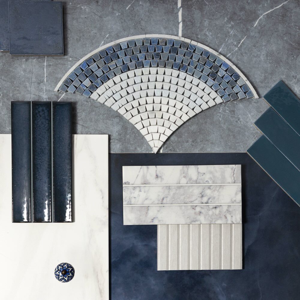 Various blue and white patterned tiles arranged in a decorative mosaic layout on marble.