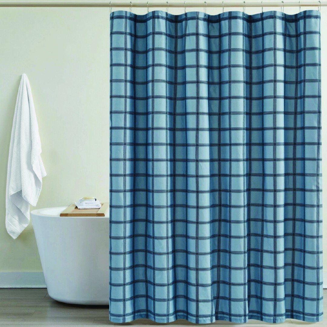 Blue plaid shower curtain hanging next to a white bathtub in a bright bathroom.