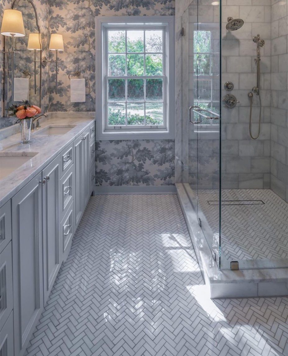 Blue and white floral wallpaper in a bright bathroom with white vanity and shower.