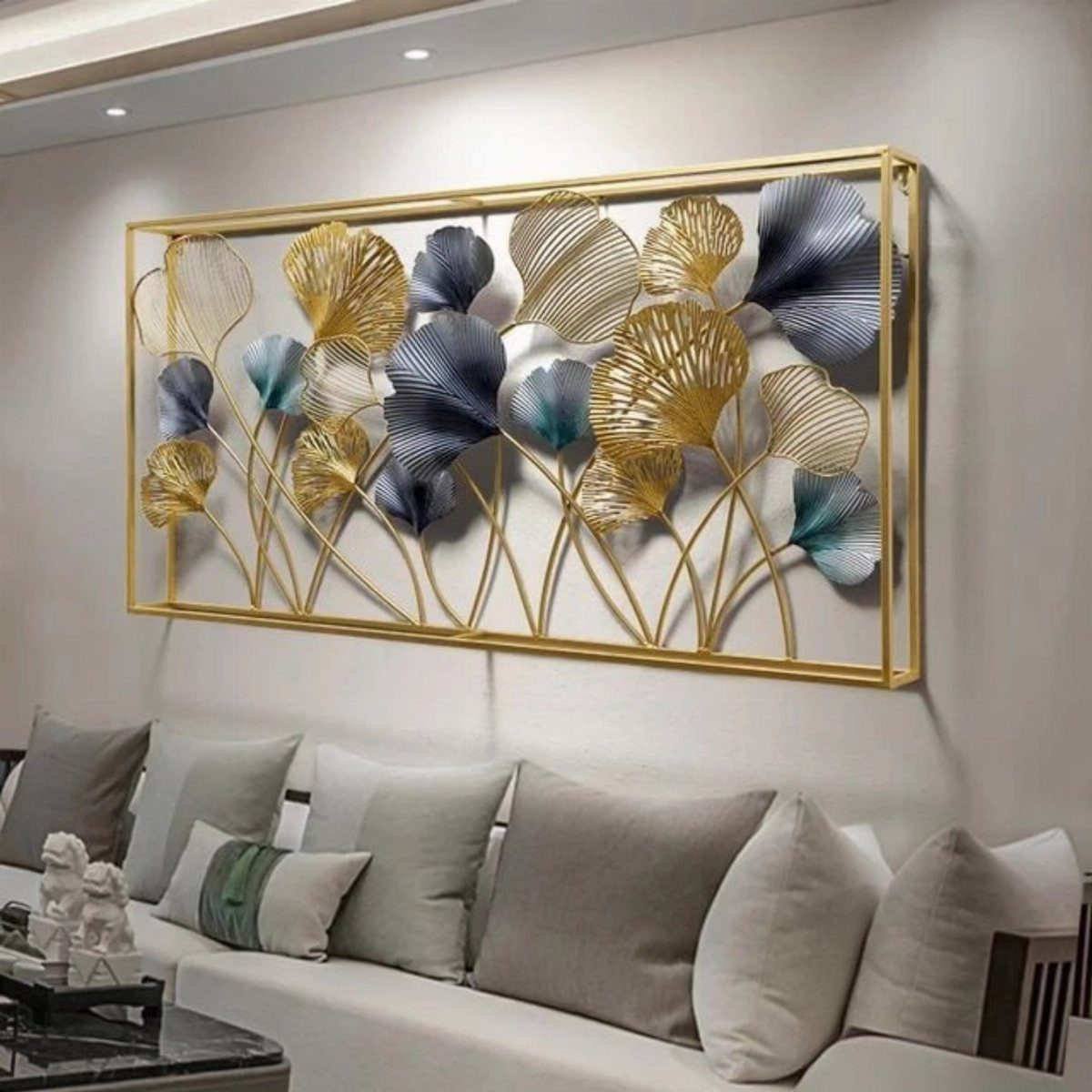 Gold and blue metallic leaf wall art hanging above a white sofa with gray pillows.