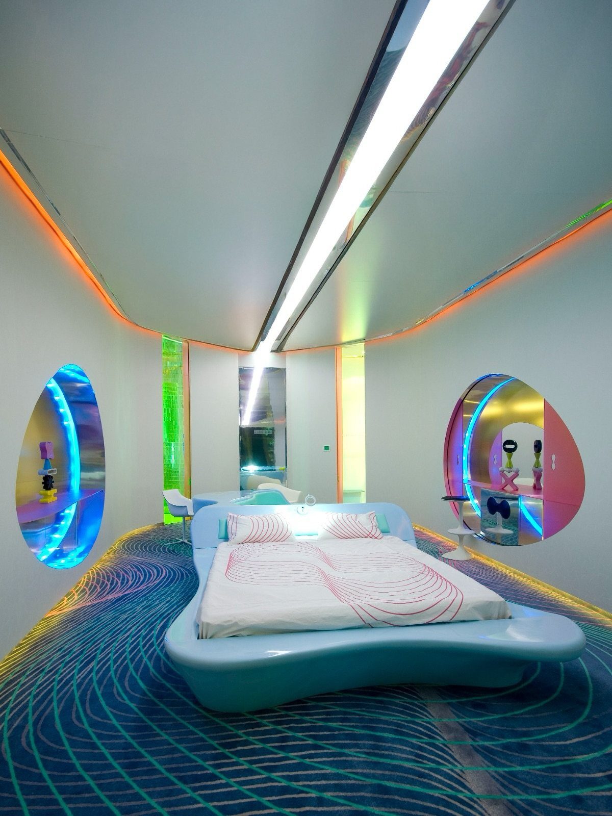Futuristic small bedroom with a light blue curved bed and glowing neon accent lighting.