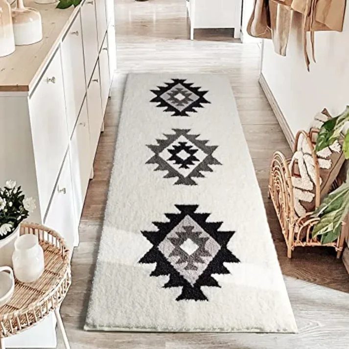 A long white textured runner rug with black geometric diamond patterns on a light wood floor.