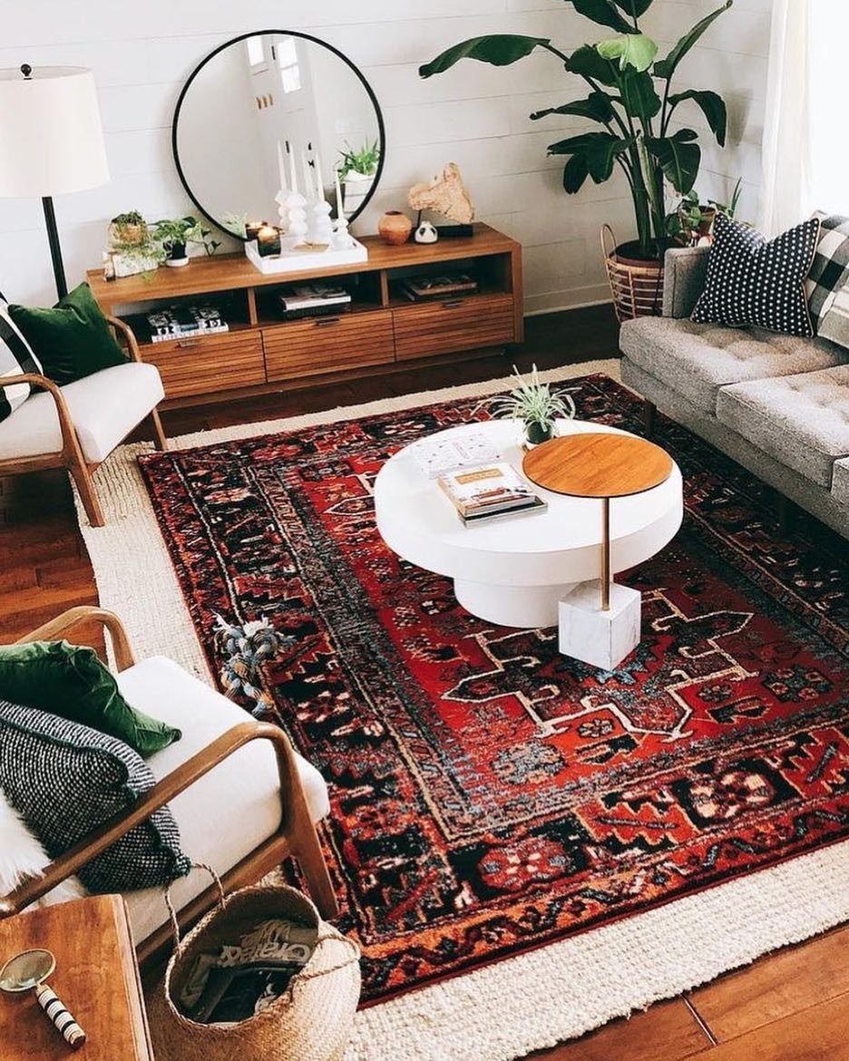 Red patterned rug layered over a cream textured rug in a boho styled living room.