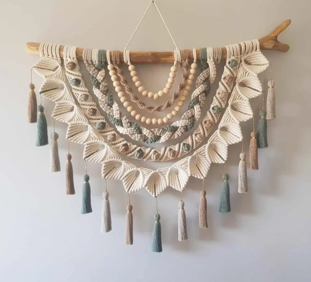 Handcrafted cream and sage green macramé wall hanging with wooden beads and tassels.