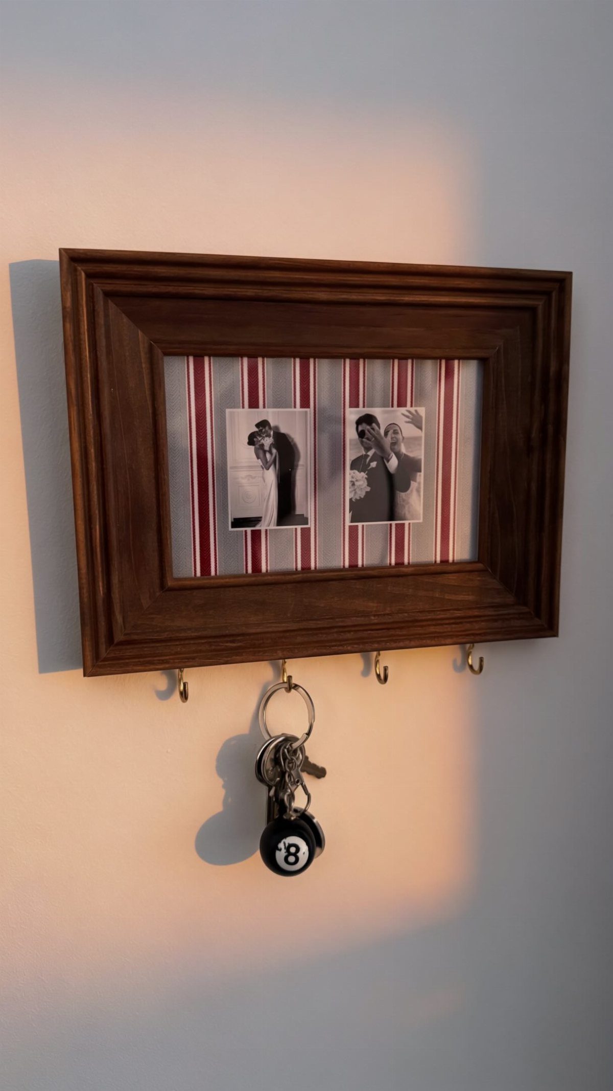 Wooden shadow box containing two black and white photos with keys hanging below.