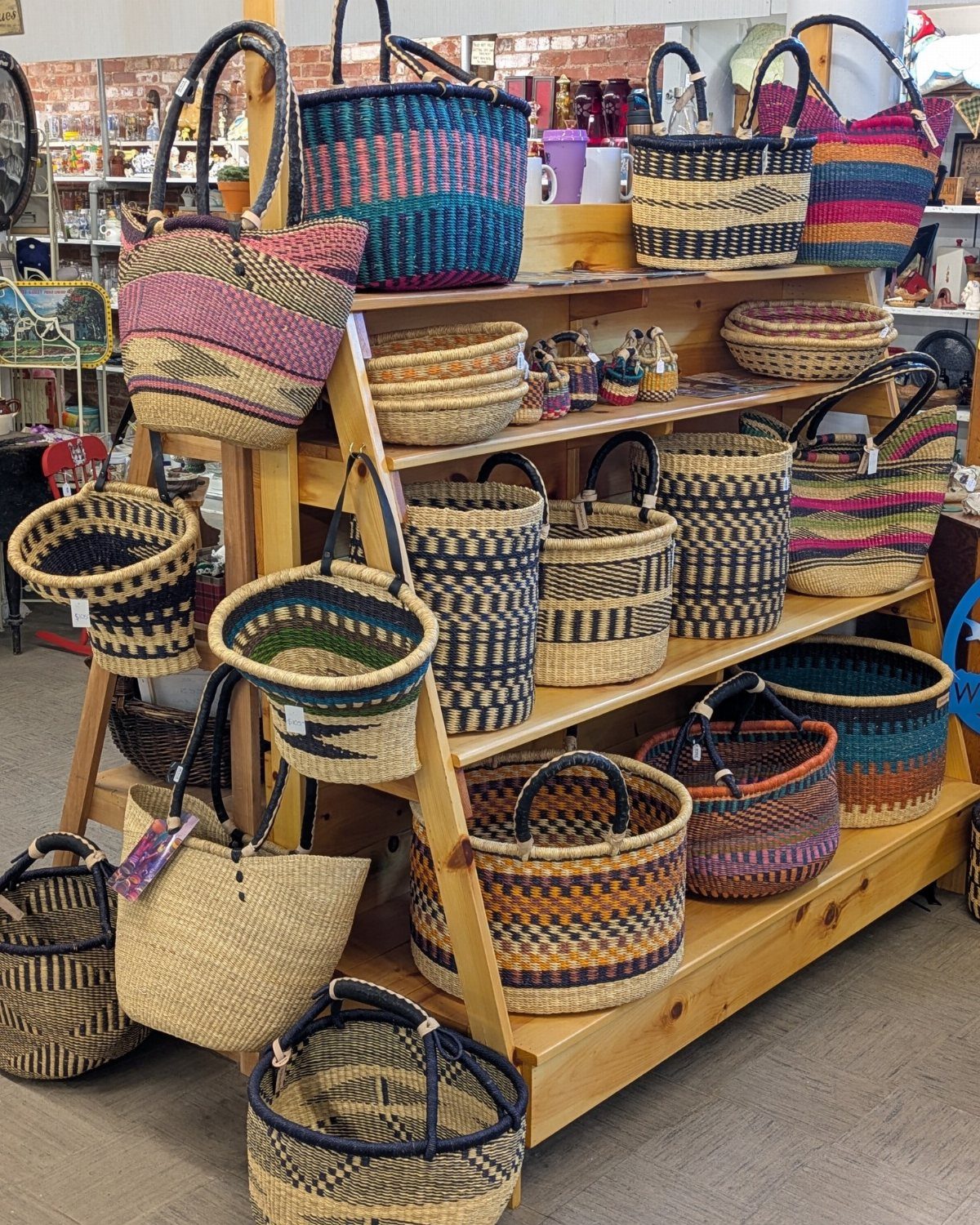 Various colorful woven baskets with handles displayed on a wooden shelving unit.