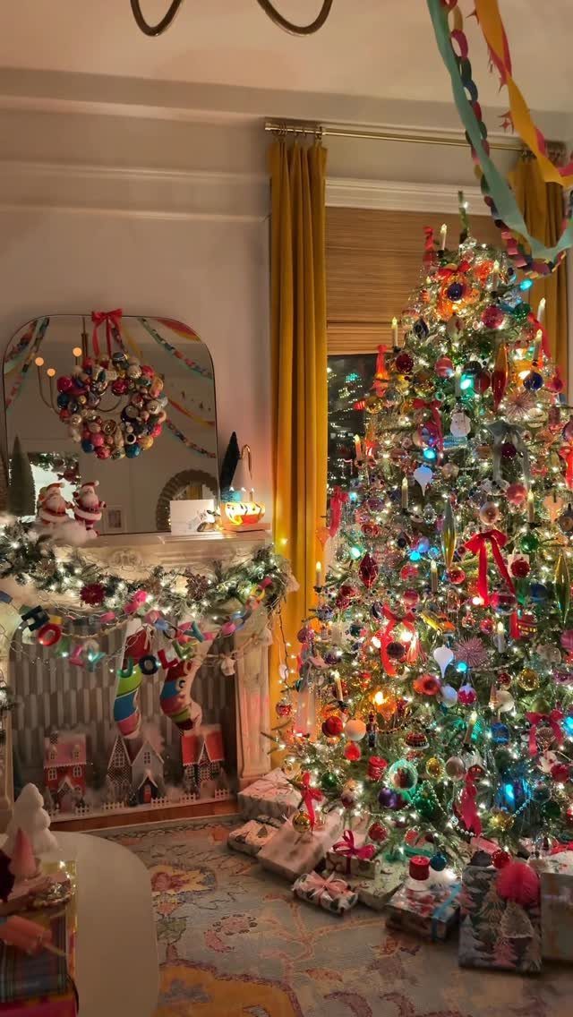 A brightly decorated Christmas tree with multicolored lights and ornaments next to a festive fireplace.