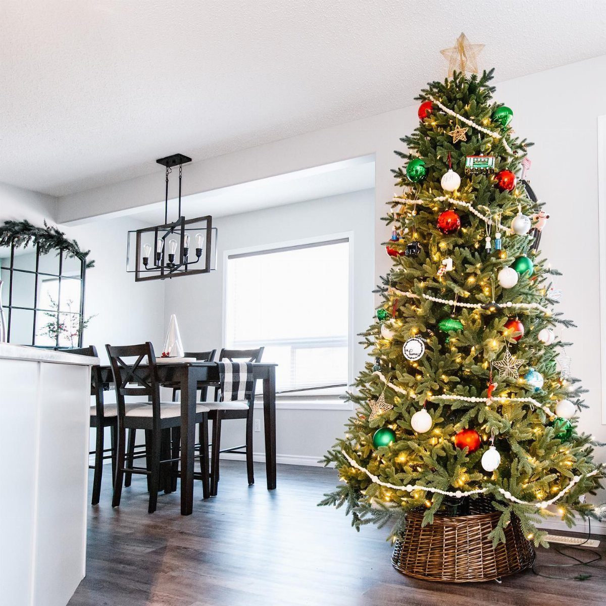 Decorated Christmas tree with a woven wicker basket collar in a bright living room.