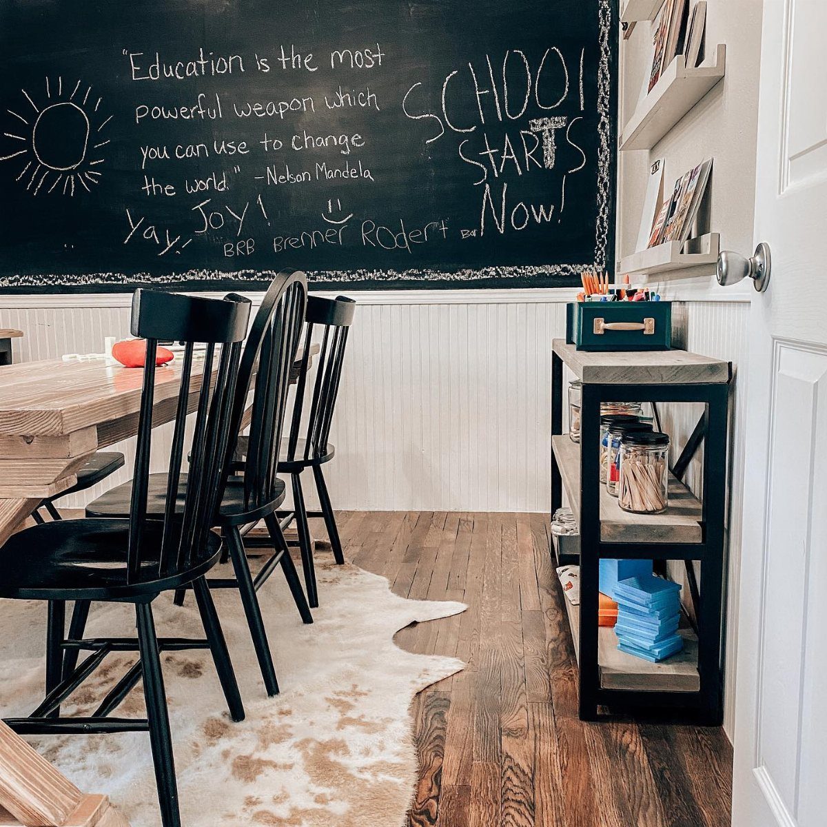 A large chalkboard wall with handwritten quotes and drawings above white wainscoting.