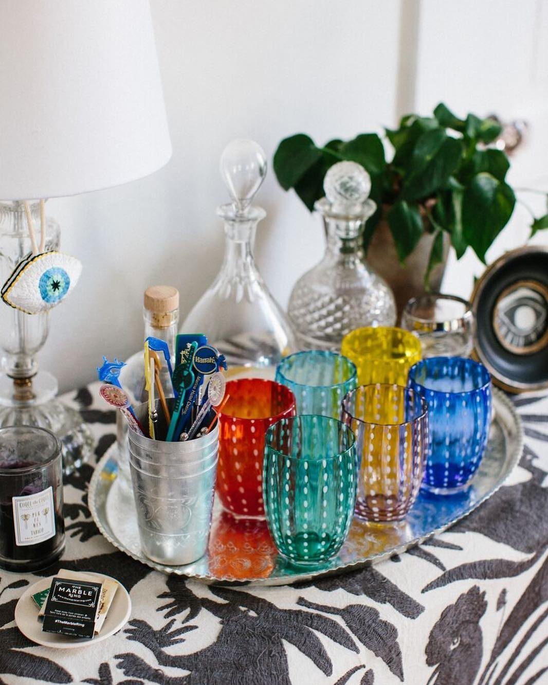 Colorful patterned glassware in red, blue, and yellow arranged on a silver tray.