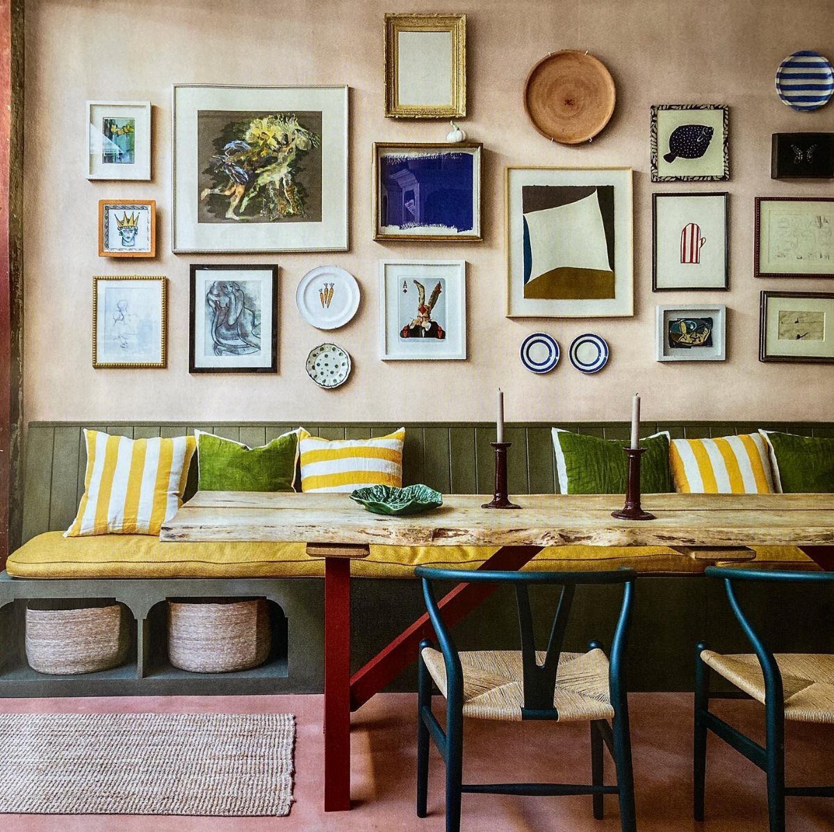 A curated gallery wall of framed art and decorative plates above a rustic dining table.