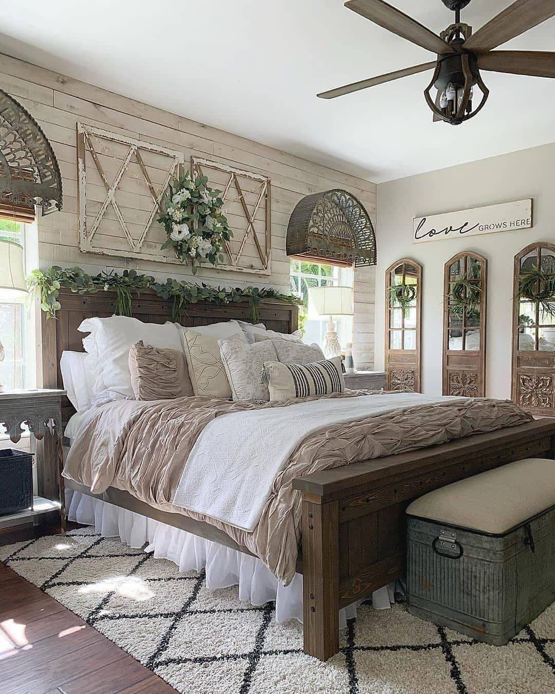 Rustic bedroom with dark wood bed, white wood paneled walls, and layered neutral bedding.