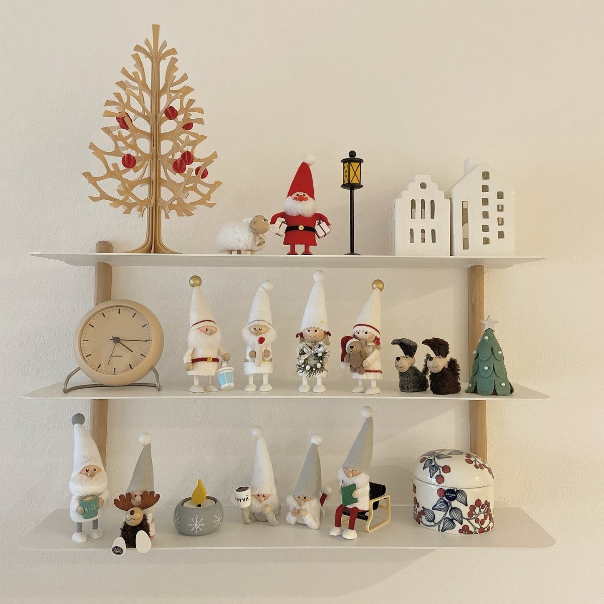 Small Christmas gnomes and festive decorations arranged on three white open kitchen shelves.