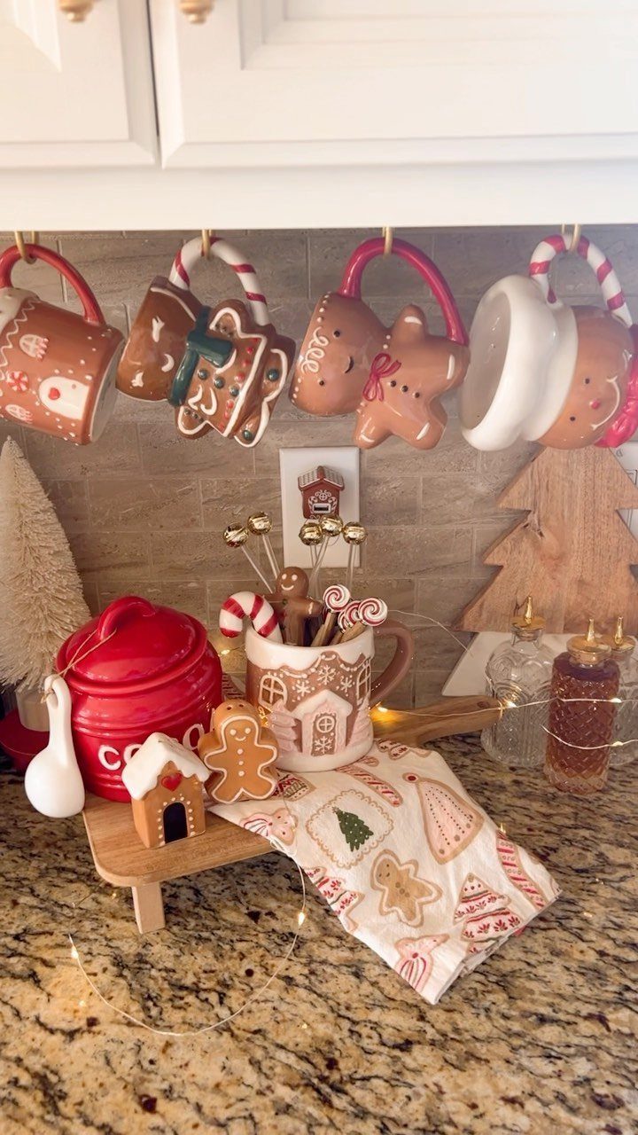 Gingerbread themed mugs, cocoa canisters, and festive cookies arranged on a kitchen countertop.