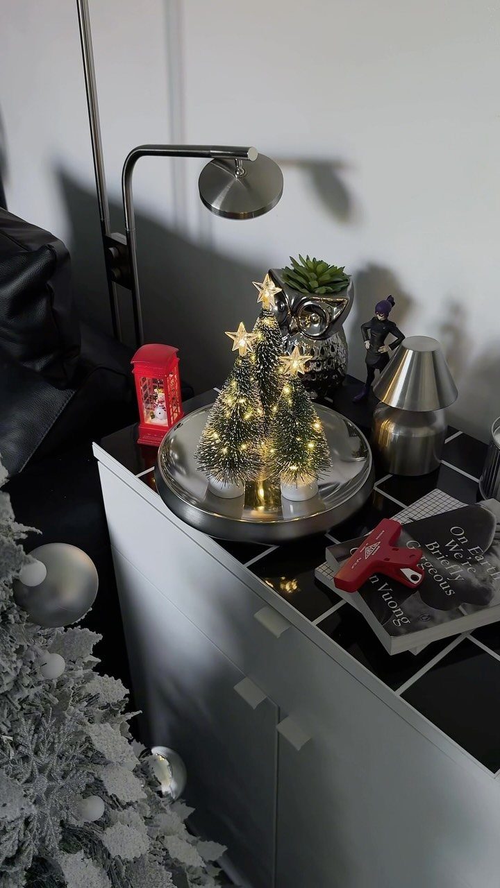 Three small sparkling Christmas trees with star toppers sitting on a silver tray.