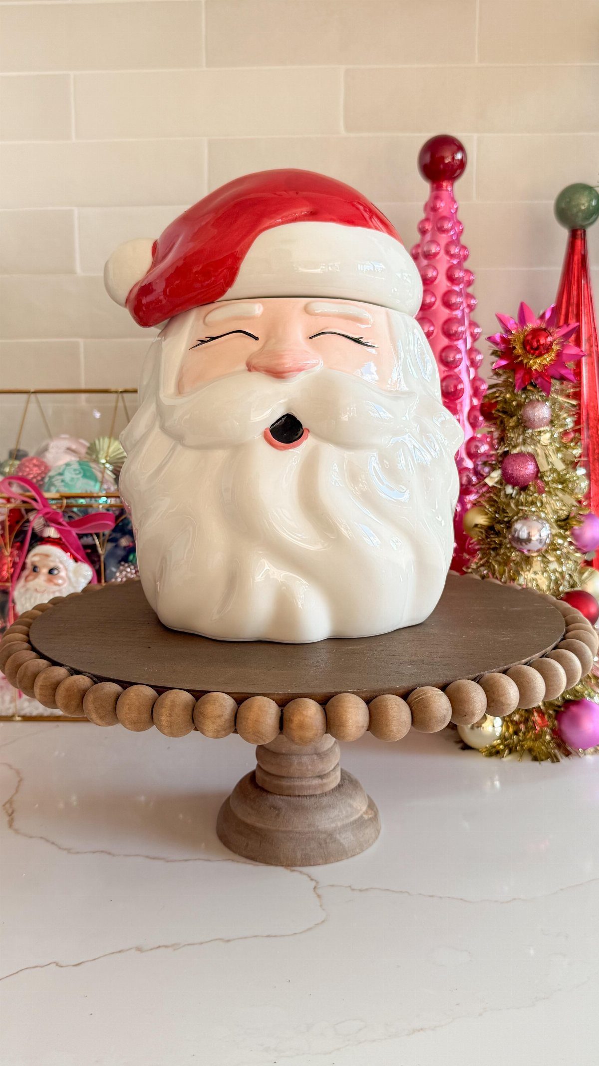 A ceramic Santa Claus cookie jar resting on a wooden beaded pedestal stand.